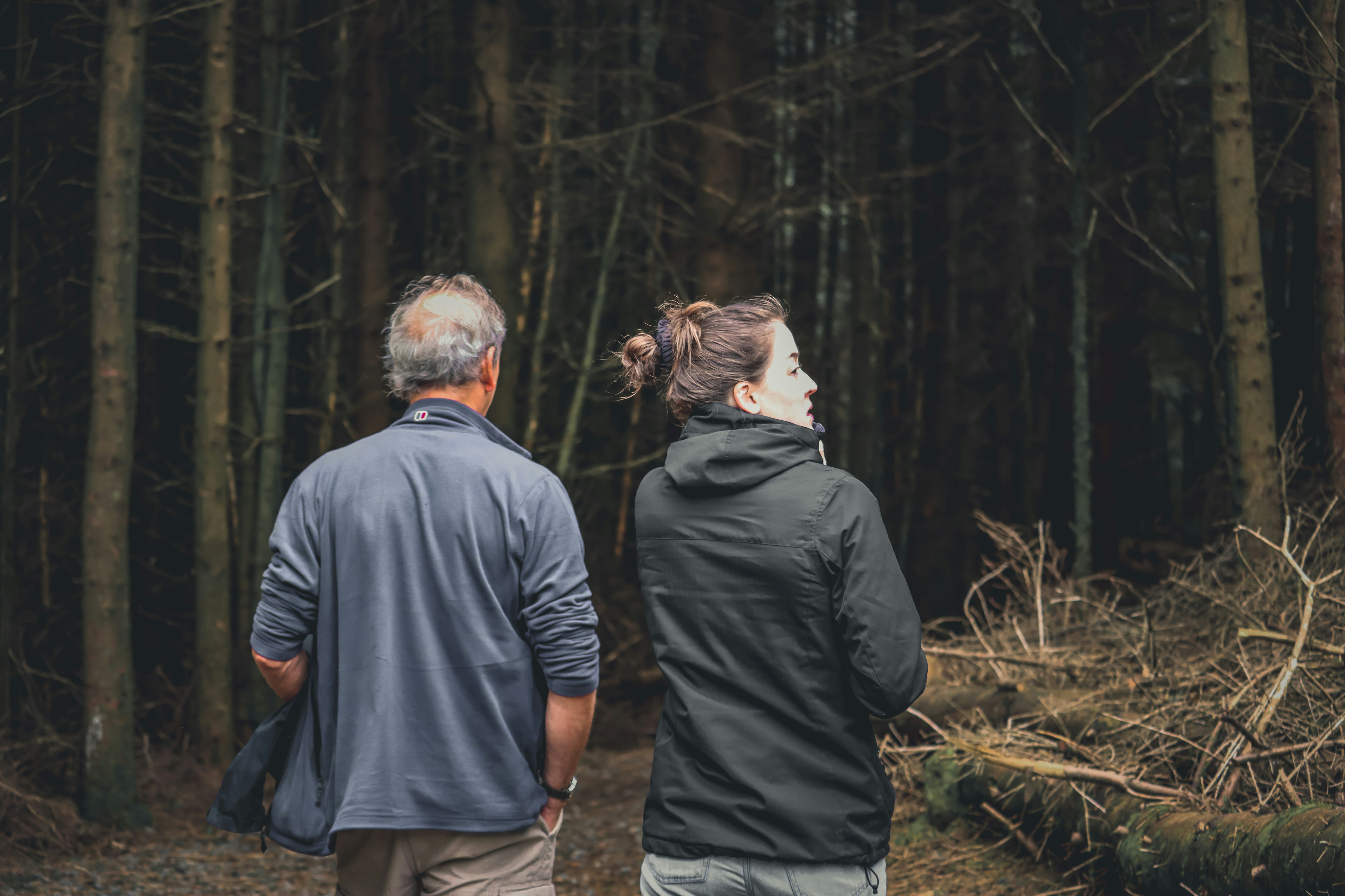 a man and a woman walking through a forest
