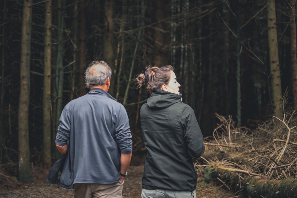 a man and a woman walking through a forest