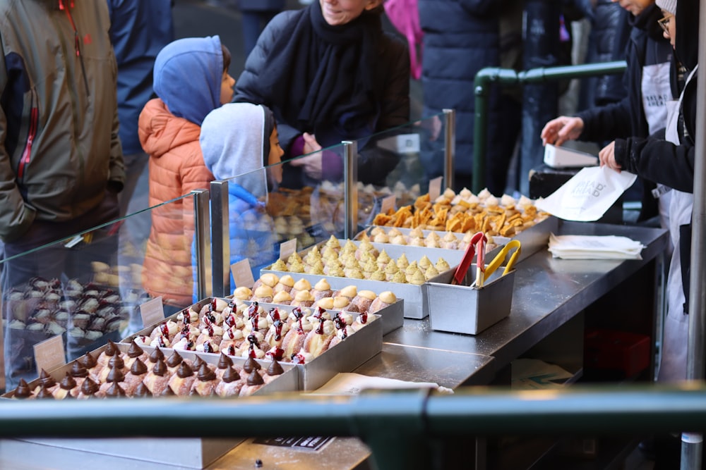 a group of people standing around a table filled with food