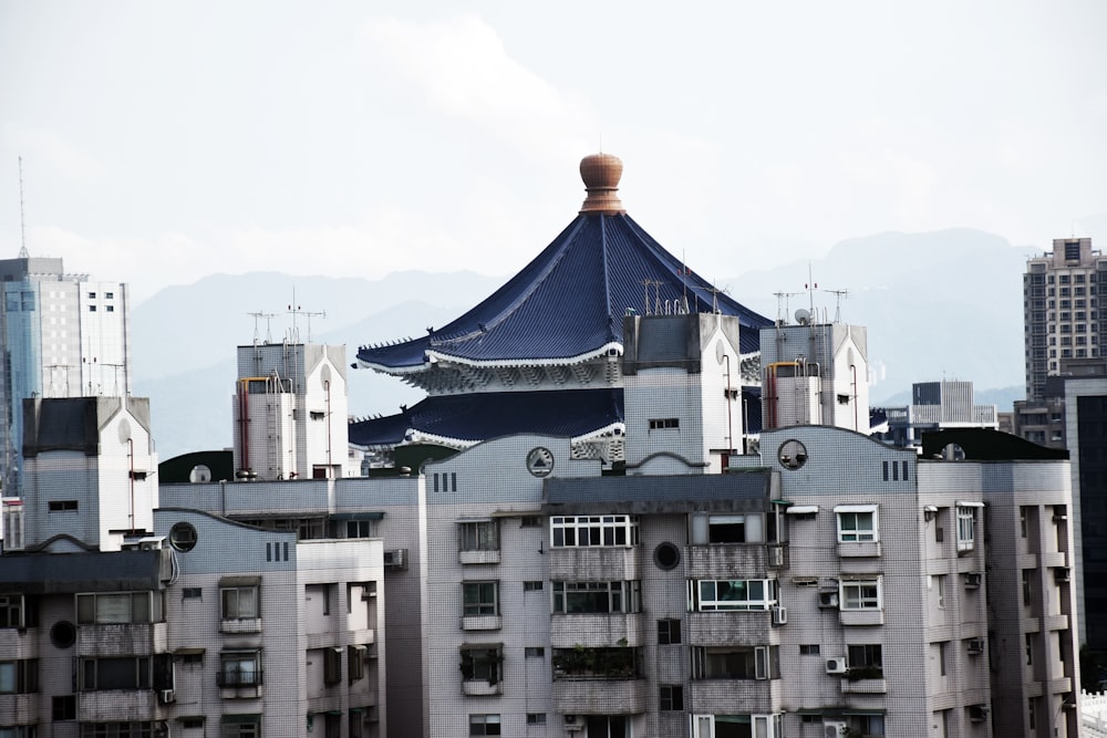 a tall building with a blue roof in the middle of a city