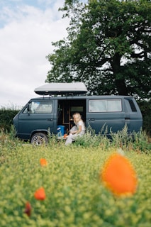 a woman sitting in a van in a field of flowers