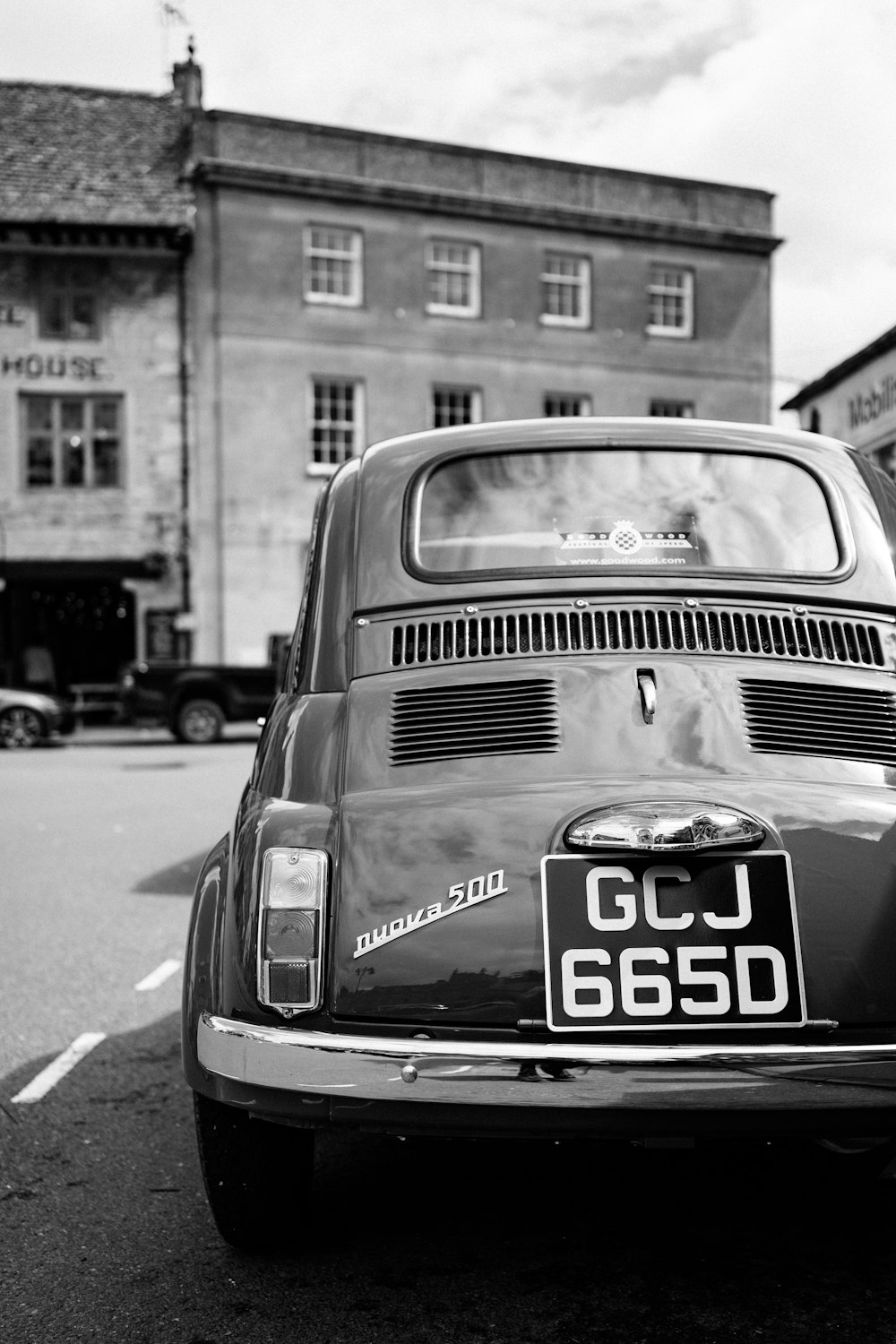 a black and white photo of a car parked in front of a building