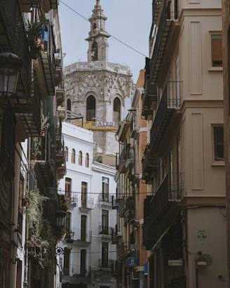 a narrow city street with buildings and a clock tower in the background