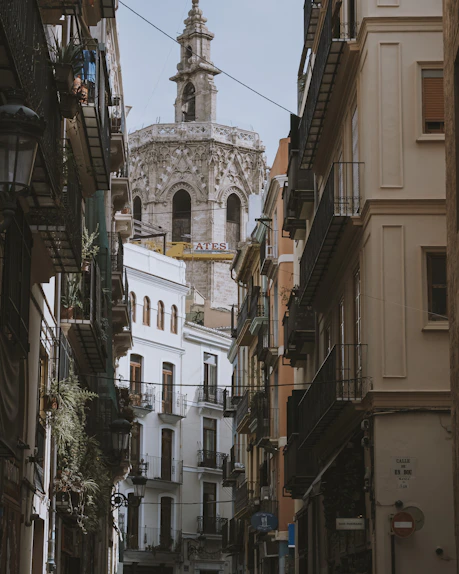 a narrow city street with buildings and a clock tower in the background