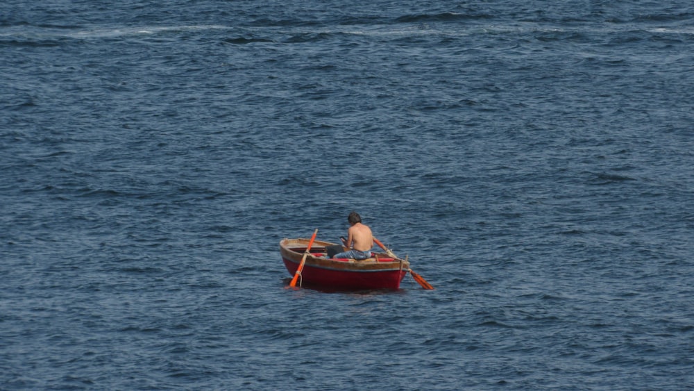 a man sitting in a small boat in the middle of the ocean