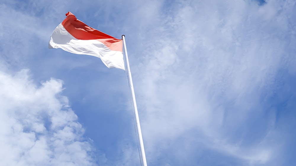Una bandera roja y blanca ondeando alto en el cielo
