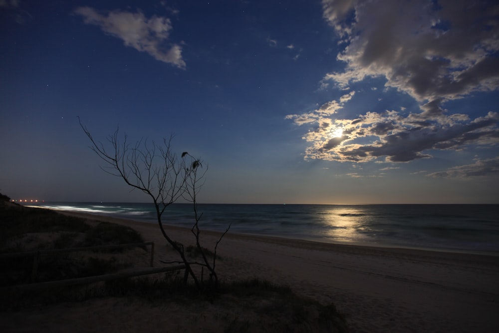 the sun is setting over the ocean on the beach