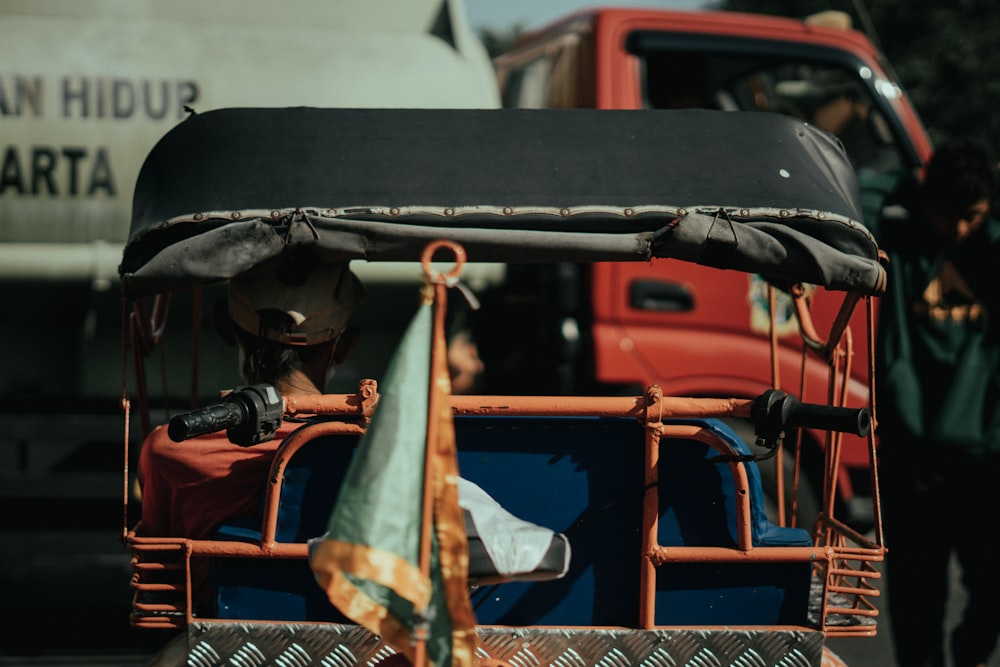 a man driving a cart down a street next to a red truck