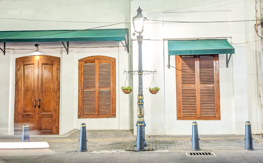 a white building with wooden shutters and green awnings