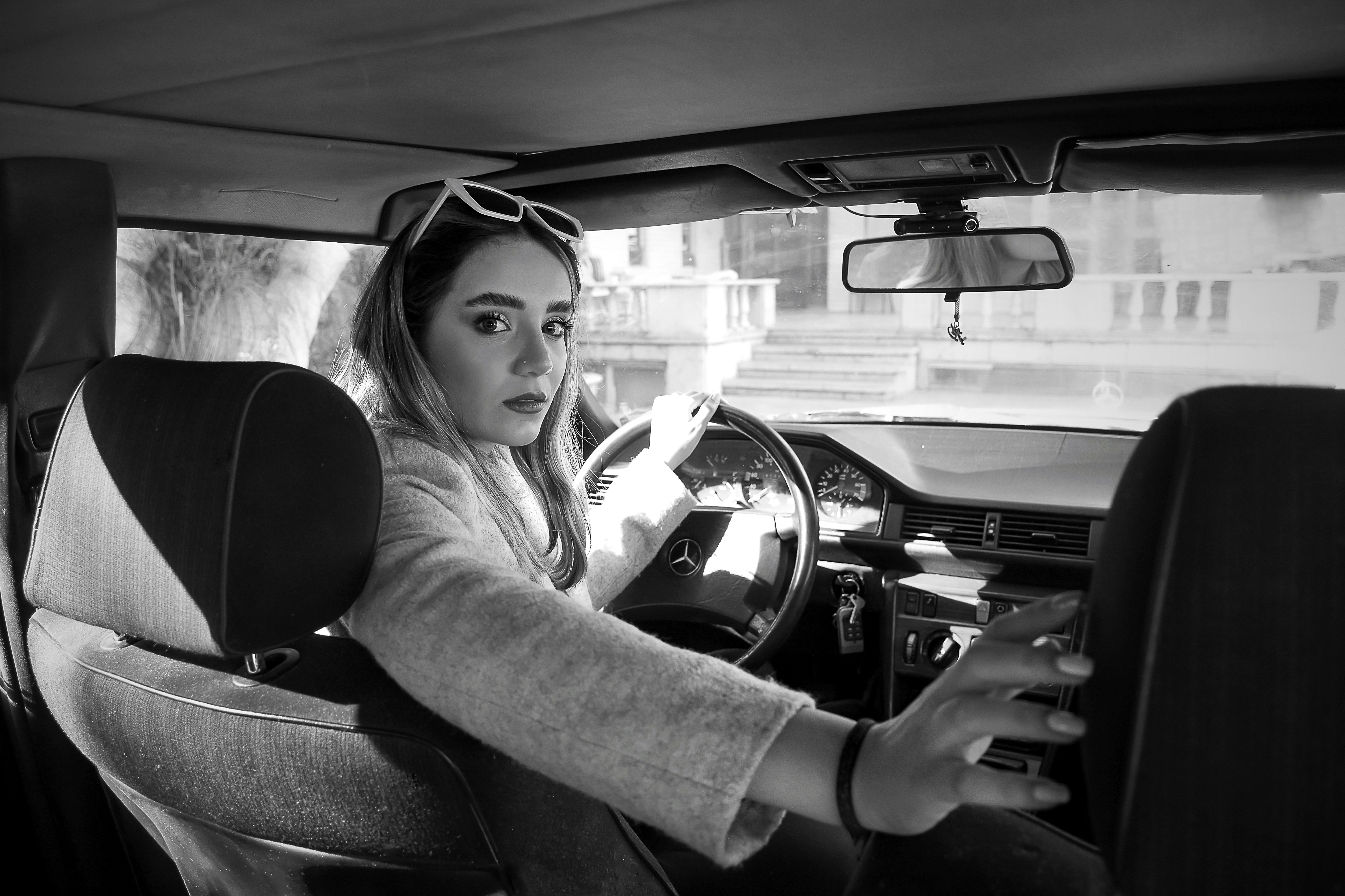 a woman sitting in a car with a steering wheel