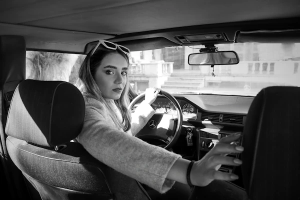 a woman sitting in a car with a steering wheel