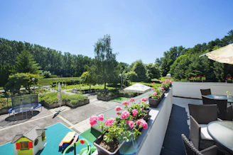 Sunny fenced garden with terrace, grill, and children's play equipment in a peaceful countryside setting.