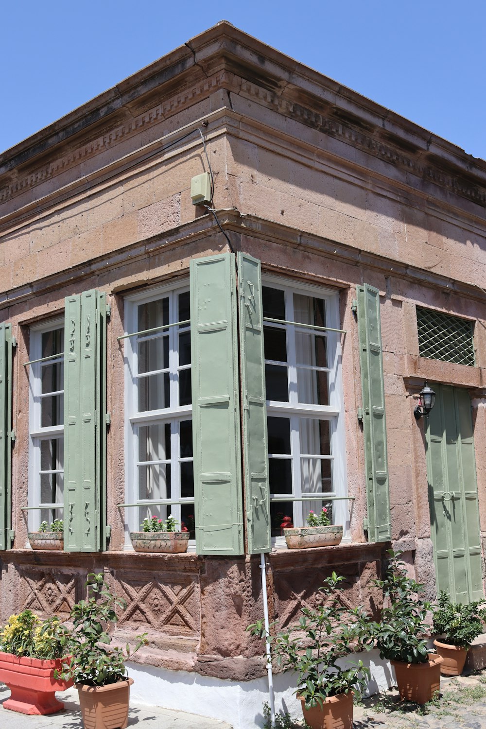 a building with green shutters and potted plants