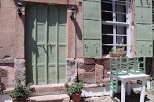 Close-up of a rustic wooden door with olive green shutters, typical of the hotel's charming style.