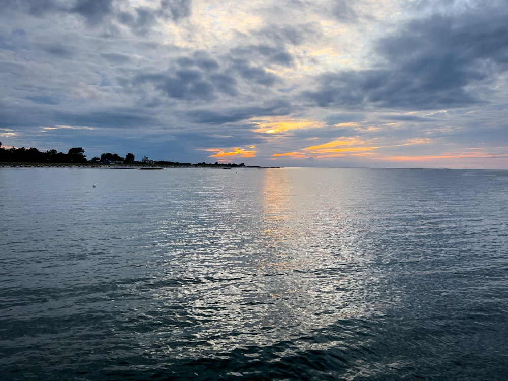 a body of water with a sky filled with clouds