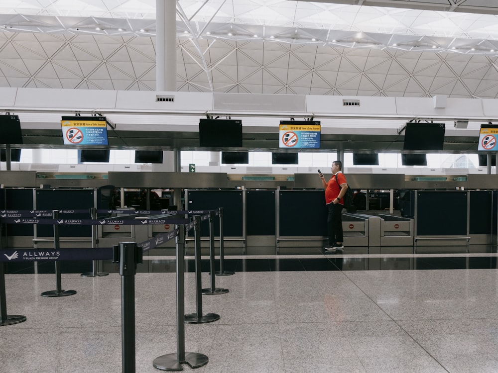 a man in a red shirt standing in an airport