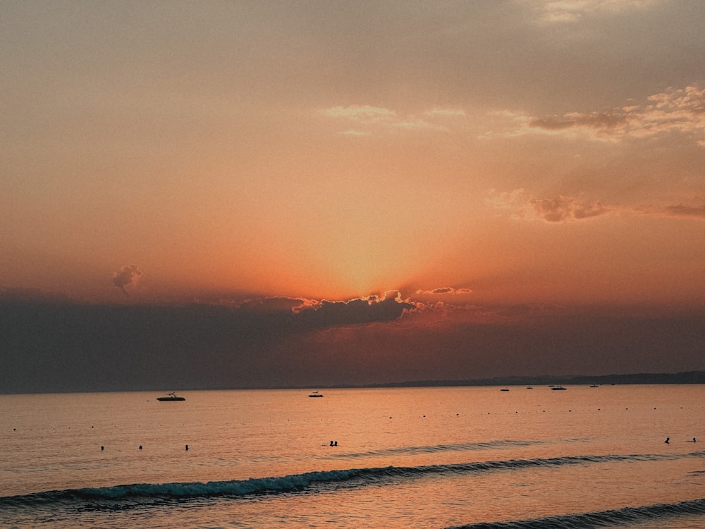 a sunset over the ocean with boats in the water