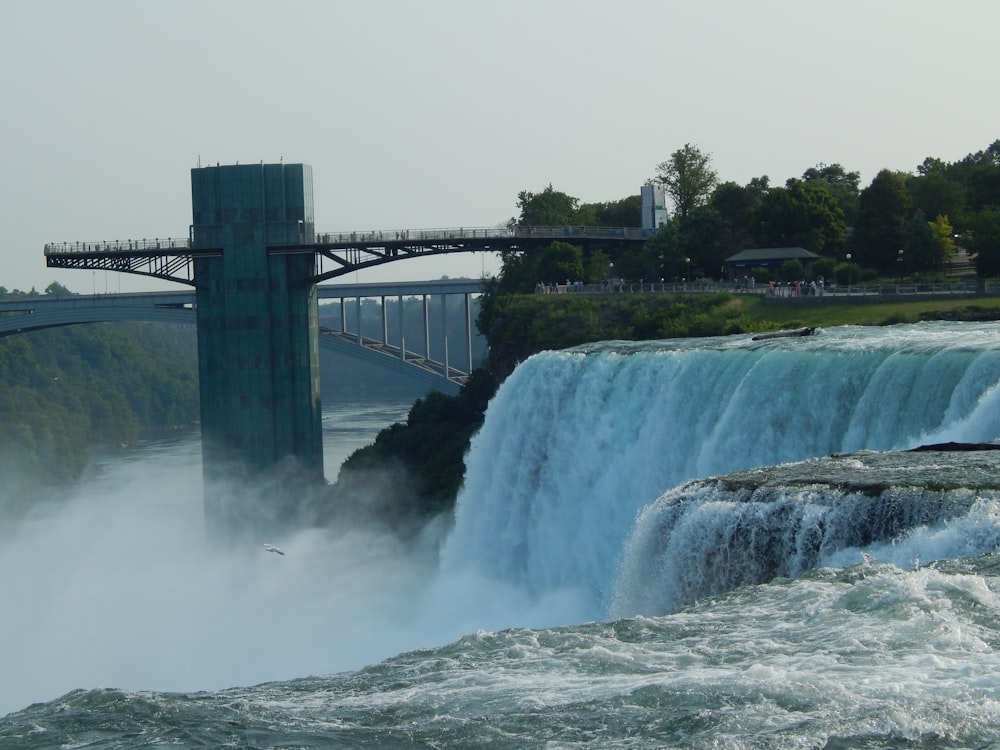 a large waterfall with a bridge over it