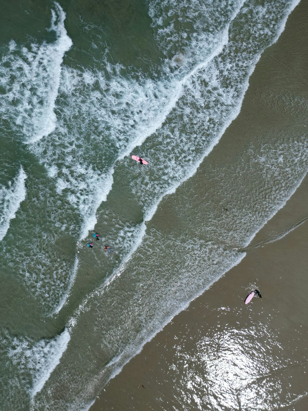 a group of people riding kiteboards on top of a wave covered beach