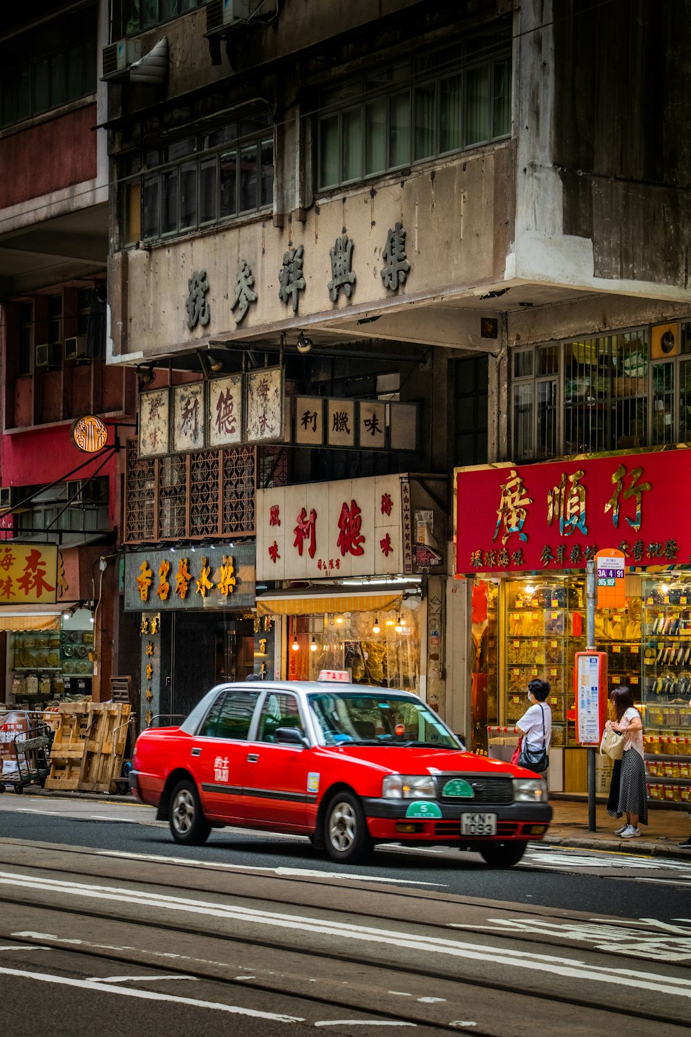 a red taxi cab driving down a street next to tall buildings