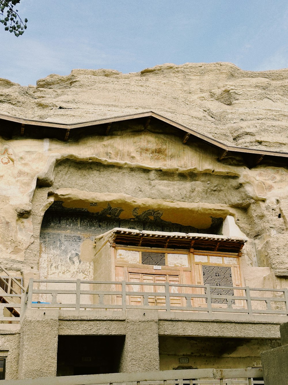 a stone building with a balcony next to a cliff