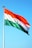 A large flag featuring three horizontal stripes of orange, white, and green, with a blue Ashoka Chakra wheel in the center. The flag is mounted on a tall flagpole against a clear blue sky.