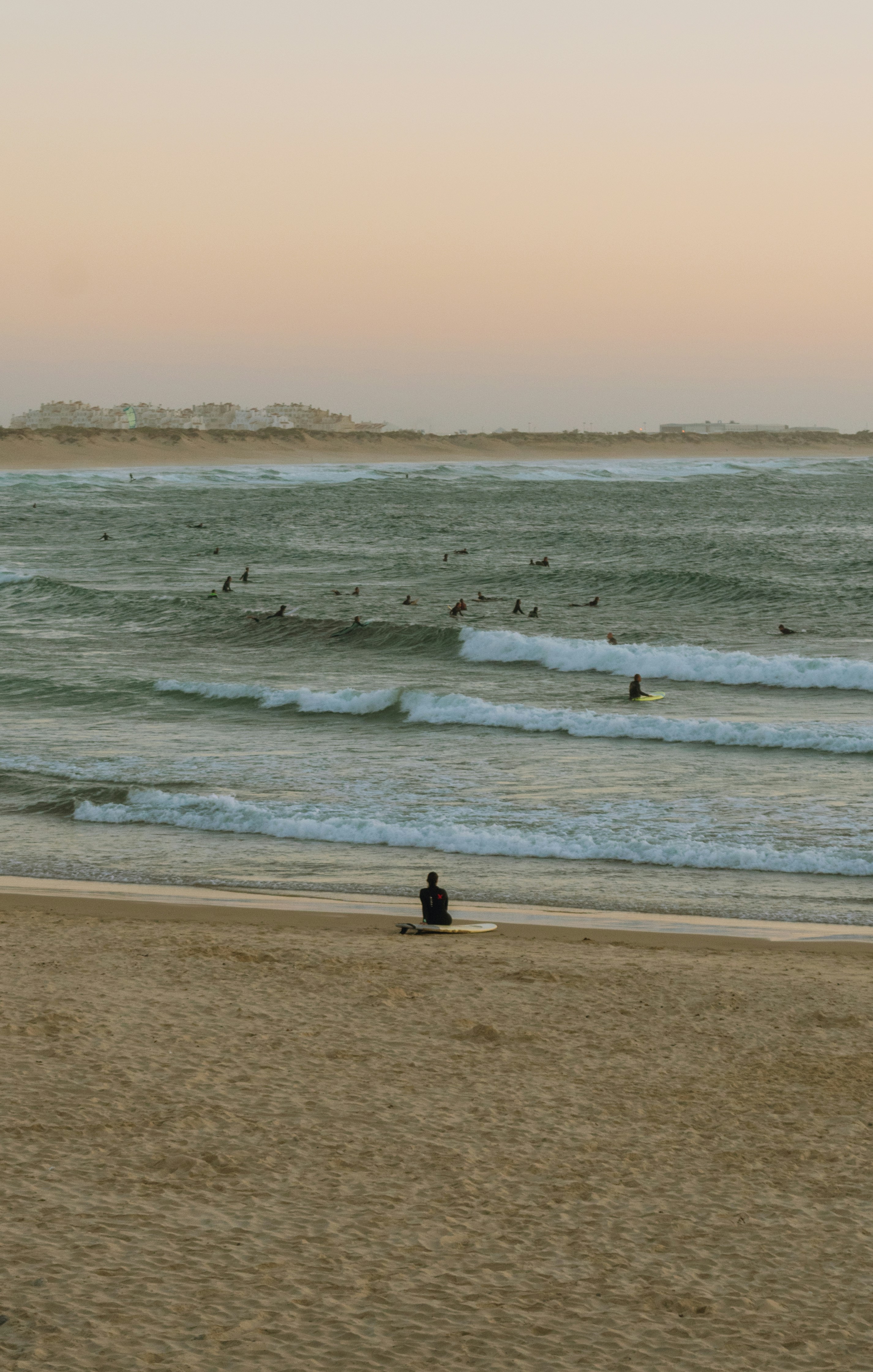 a person sitting on a surfboard on the beach