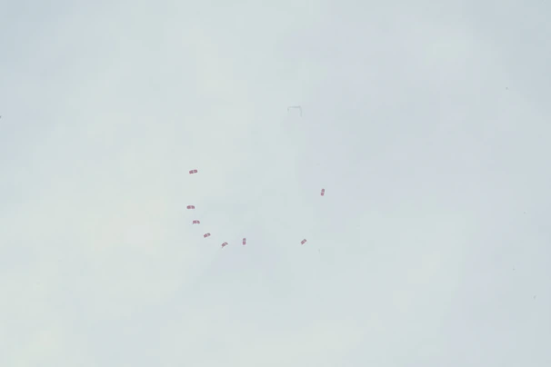 A vibrant aerial shot of skydivers freefalling in formation against a bright blue sky.