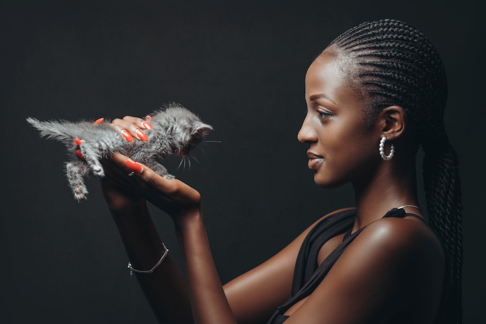 a woman holding a small kitten in her hands