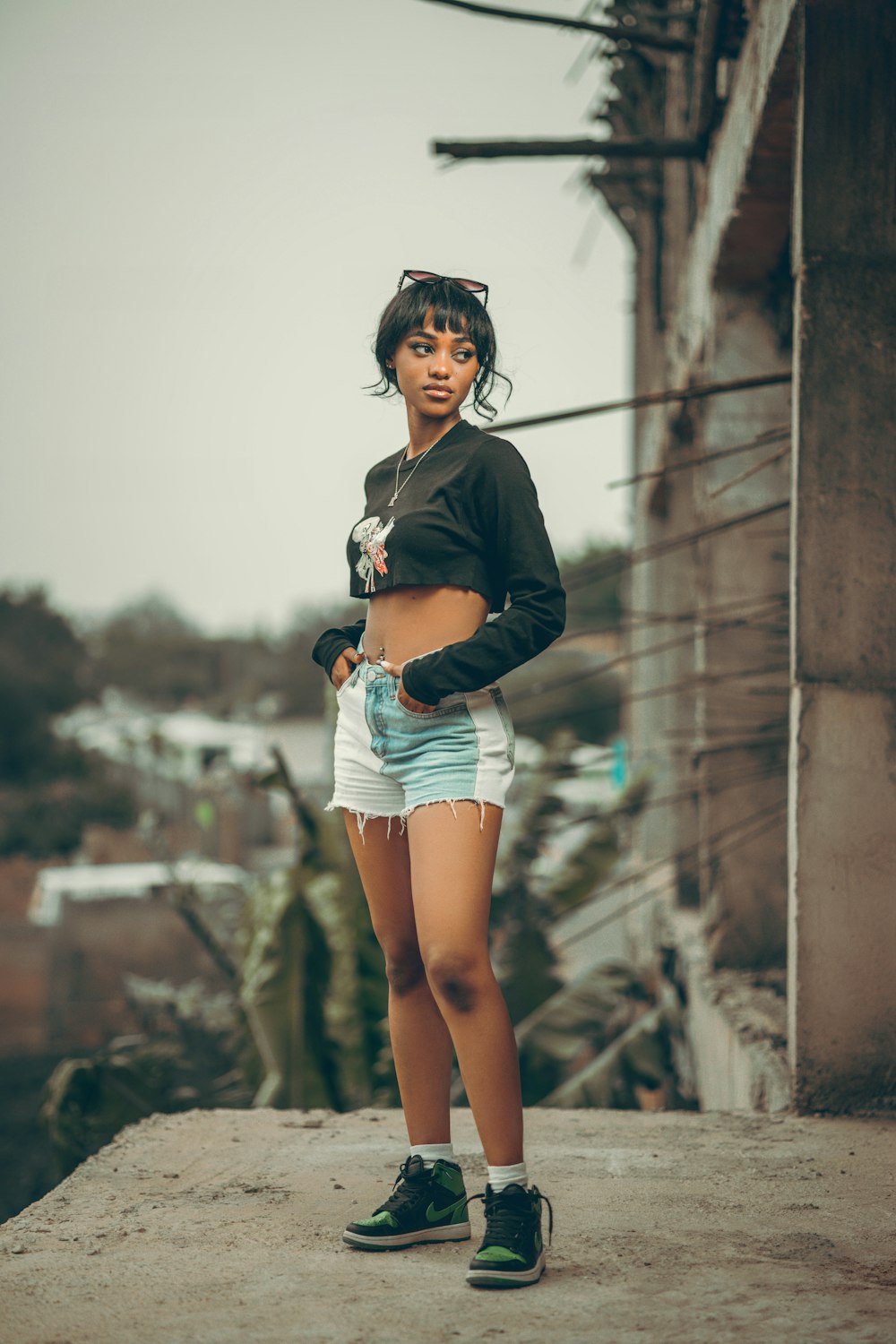 a woman standing on a ledge with her hands in her pockets