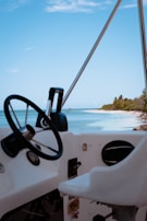 Close-up of a boat’s polished wooden steering wheel with the ocean in the background.