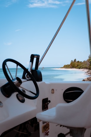 A close-up of the boat’s wooden steering wheel with the ocean and sky in the background.
