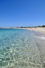 A scenic beach with turquoise water and a relaxed traveler soaking up the sun on a long vacation