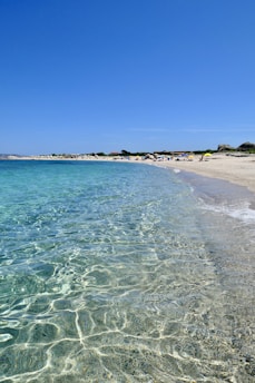 A scenic beach with turquoise water and a relaxed traveler soaking up the sun on a long vacation