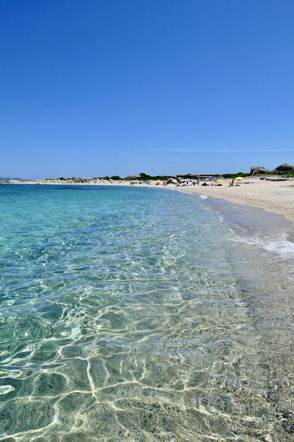 a beach with clear blue water and a sandy shore