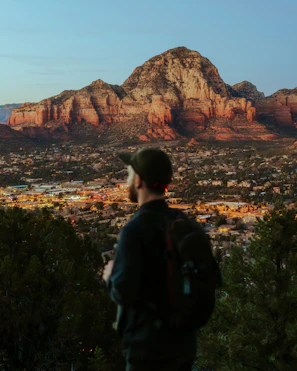 A traveler with a backpack looking at a city skyline during golden hour.