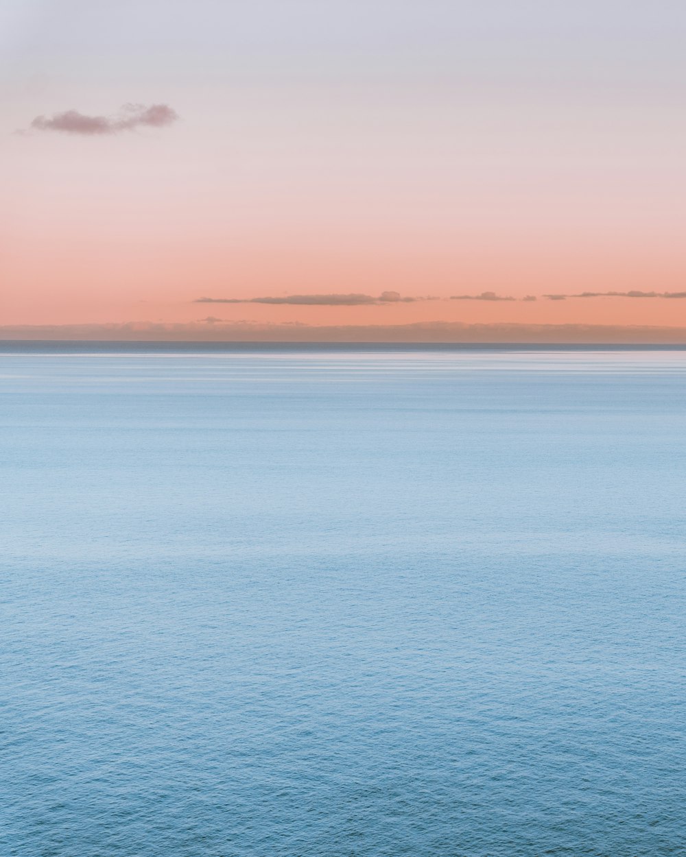 a large body of water sitting under a pink sky