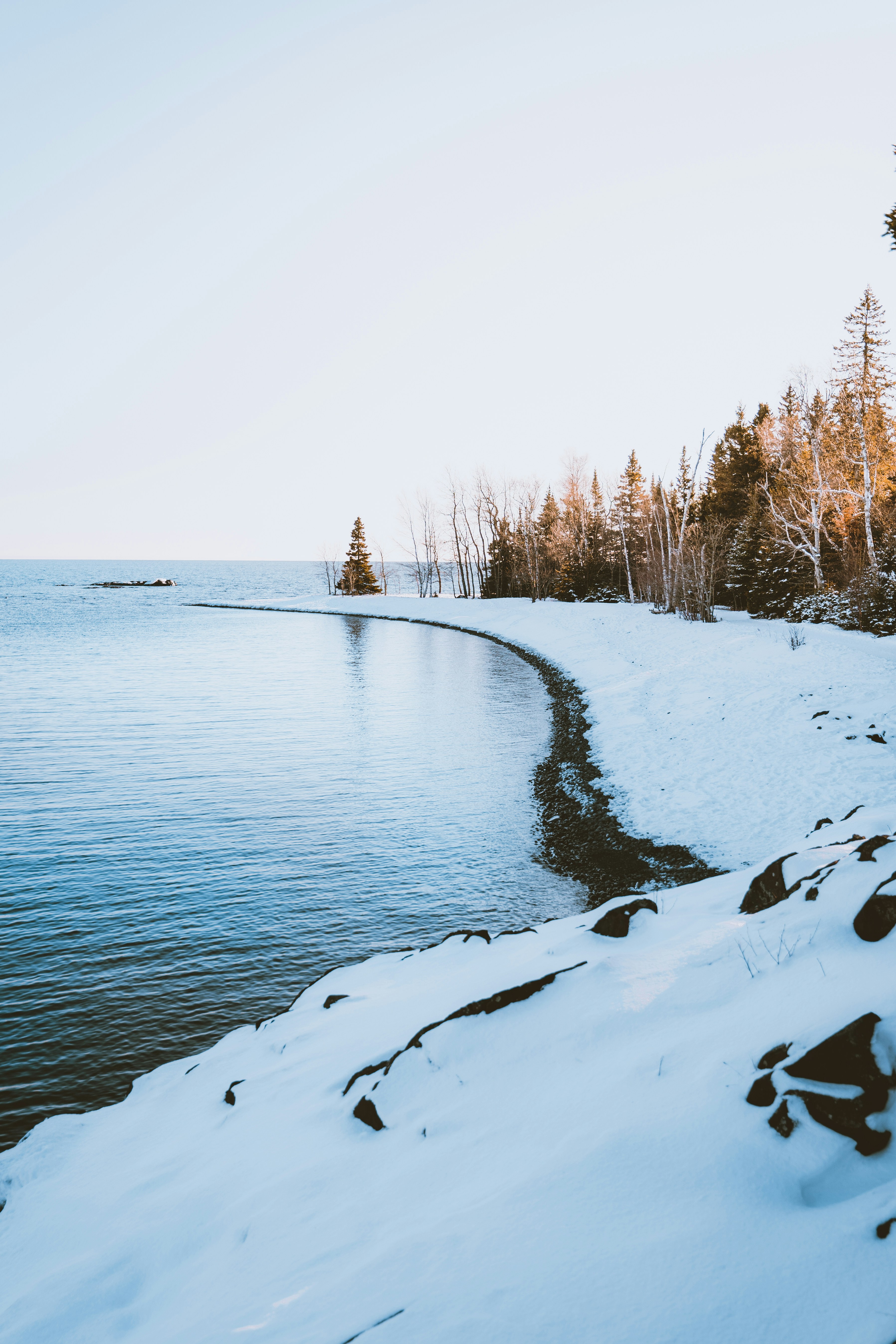 a body of water surrounded by snow covered ground