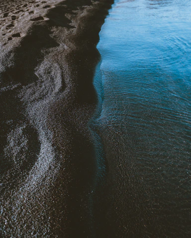 A serene close-up of natural textures blending water and sand, evoking calm and purity.