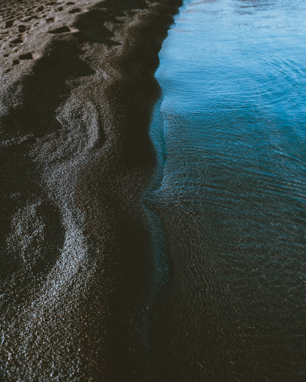 un cuerpo de agua sentado junto a una playa de arena