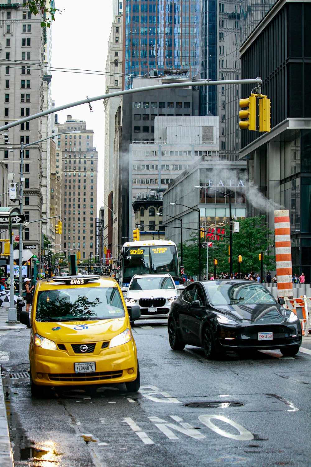 Un taxi amarillo conduciendo por una calle junto a un coche negro