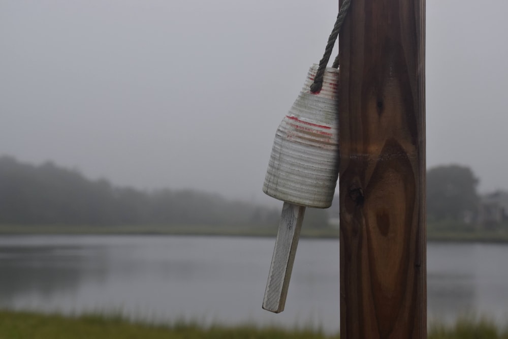 a bird feeder hanging from a wooden post next to a lake