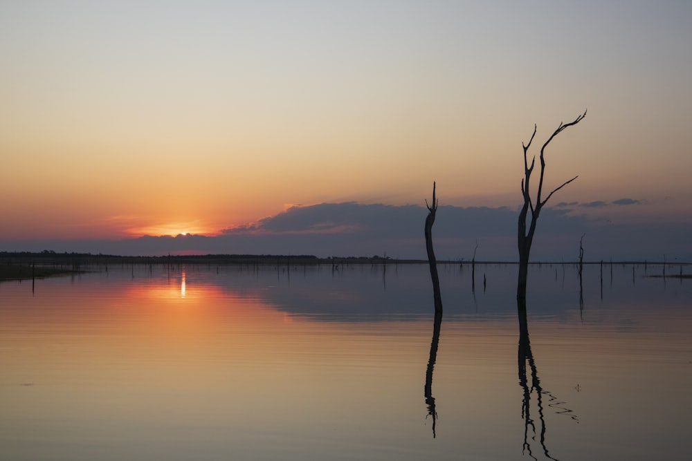 the sun is setting over a calm lake