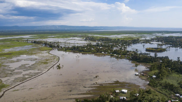 A flooded village in Assam with submerged houses and stranded families seeking shelter.