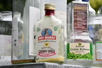 An assortment of gourmet sauces and dressings in glass bottles with fresh herbs and spices scattered nearby
