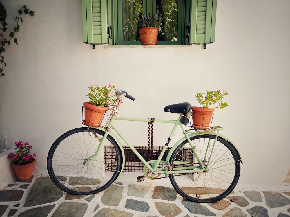 a green bike parked next to a window with green shutters