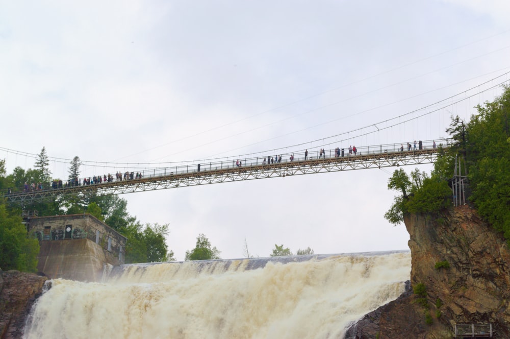 a group of people standing on a bridge over a waterfall