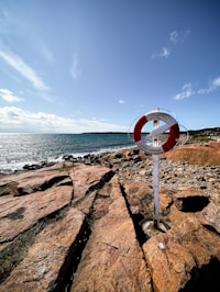 a red and white sign sitting on top of a rocky beach