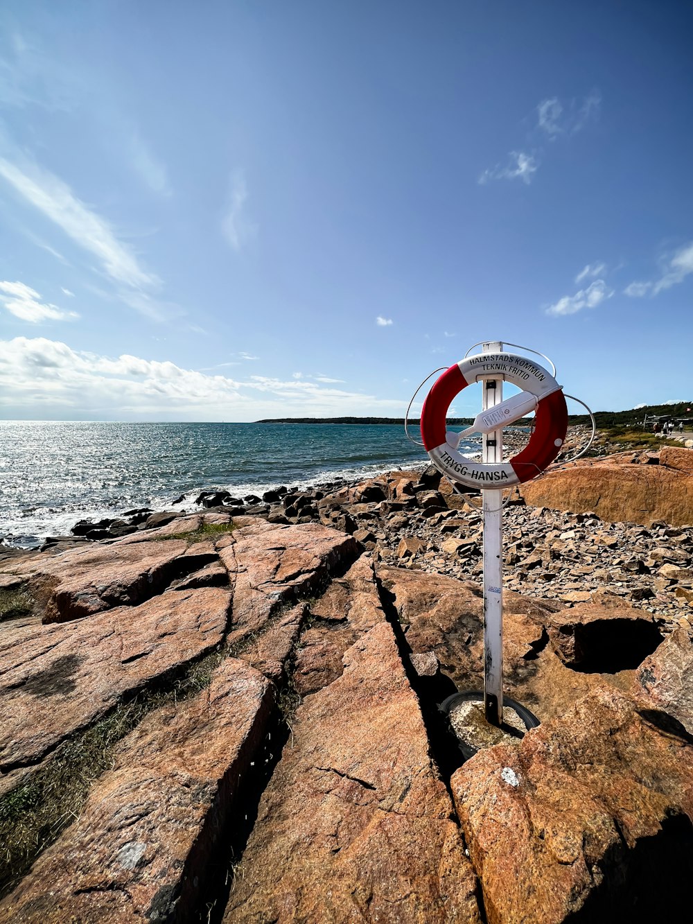a red and white sign sitting on top of a rocky beach