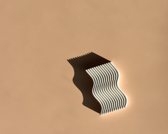 Portrait-style photo of a helix sculpture floating with subtle shadow shifts on a clean white background.